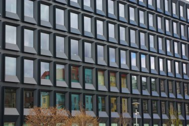 Dikdörtgen cam paneller ve dikey renk aksanları olan büyük, modern bir bina..