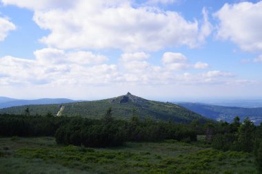 Vadisi, mavi gökyüzü ve yeşil ağaçları olan bir dağ manzarası..