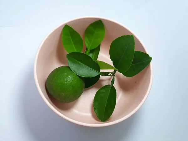 Beyaz kireç rengi aurantiifolia meyvesi ve yaprakla izole edilmiş. Uzay bitkisi, baharat ve malzemeyi kes.