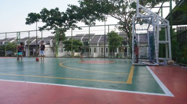 Surabaya, East Java, Indonesia - January, 2023 : the children spent the afternoon barefoot playing soccer on the futsal cement field near the house     