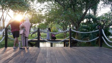 Surabaya, East Java, Indonesia - January, 2023 : Cinematic sunset at public park when hijab women spending time together taking selfie picture    