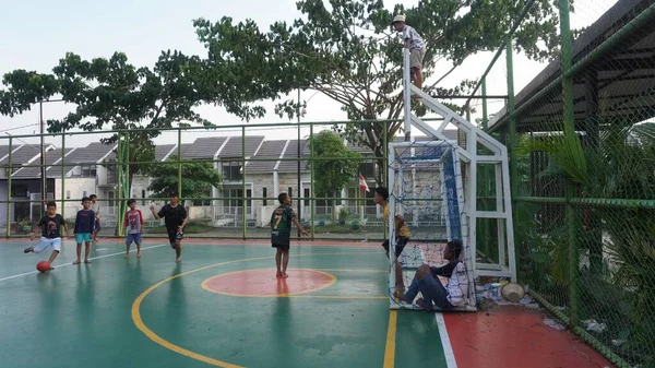 Surabaya, East Java, Indonesia - January, 2023 : the children spent the afternoon barefoot playing soccer on the futsal cement field near the house     