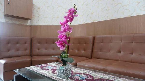 interior design of a brown sofa with pink flower decoration on the table in the office waiting room, clinic or living room