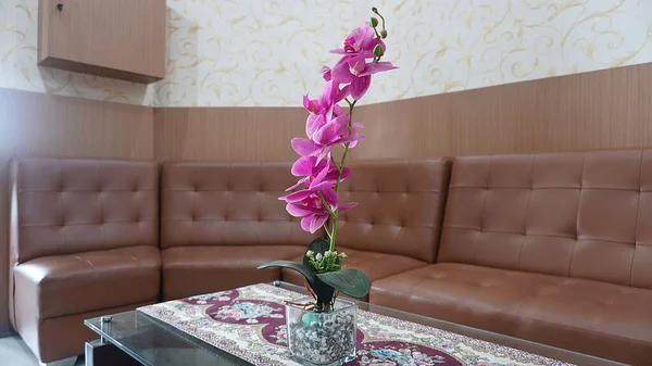 interior design of a brown sofa with pink flower decoration on the table in the office waiting room, clinic or living room