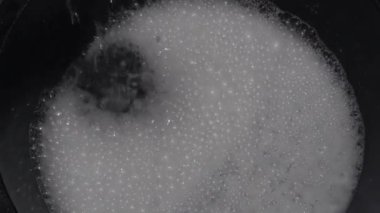 water flowing from the faucet on the laundry detergent makes foam in a bucket in preparation for washing clothes