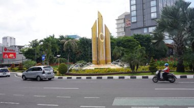 Surabaya, East Java, Indonesia - February, 2023 : traffic on the Bambu runcing or sharp bamboo monument. iconic history of independence using traditional weapons from bamboo    