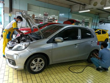 Bir araba tamircisi arabayı inceliyor. Surabaya, Doğu Java, Endonezya. 18 Aralık 2022