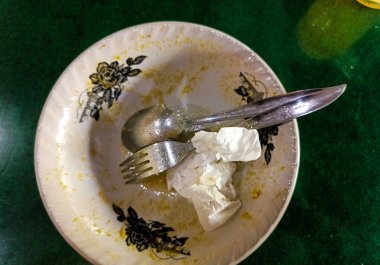 Yemekten sonra çatallı, kaşıklı ve kirli mendilli beyaz tencere. Surabaya, Doğu Java, Endonezya. 09 Ocak 2023