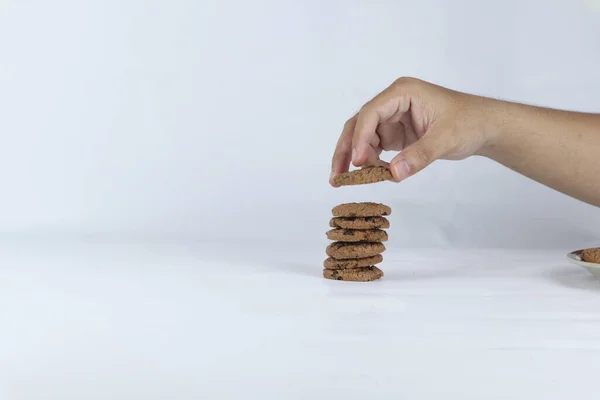 stock image hands stacking cookies on a white background. Human hand taking oat cookie from a stack