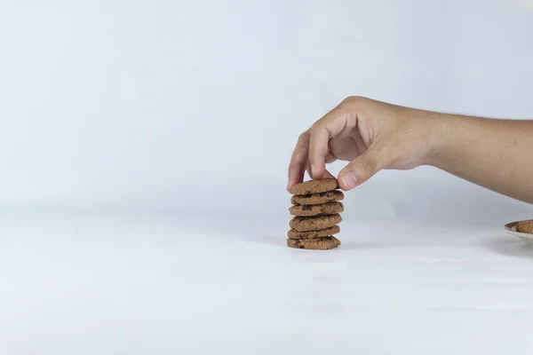 stock image hands stacking cookies on a white background. Human hand taking oat cookie from a stack