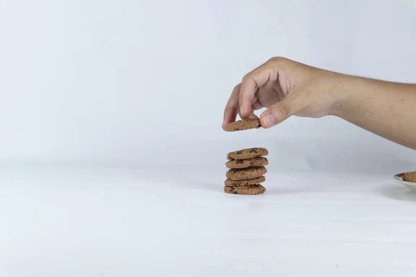 hands stacking cookies on a white background. Human hand taking oat cookie from a stack