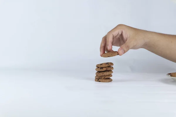 hands stacking cookies on a white background. Human hand taking oat cookie from a stack