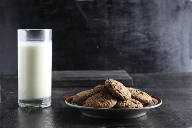 Siyah arka planda kurabiye ve süt. Metin için boşluk