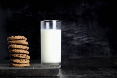 Siyah arka planda kurabiye ve süt. Metin için boşluk