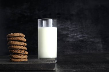 Siyah arka planda kurabiye ve süt. Metin için boşluk