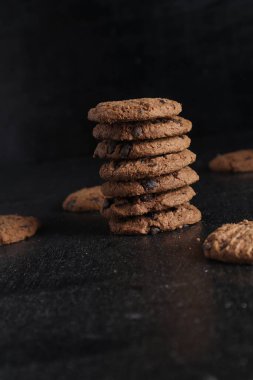 Siyah arka plandaki tahta masada bir yığın çikolatalı kurabiye.
