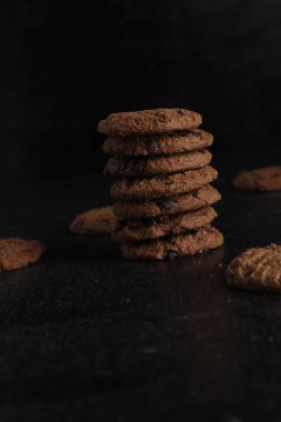 Siyah arka plandaki tahta masada bir yığın çikolatalı kurabiye.