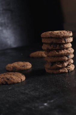 Siyah arka plandaki tahta masada bir yığın çikolatalı kurabiye.