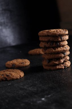 Siyah arka plandaki tahta masada bir yığın çikolatalı kurabiye.