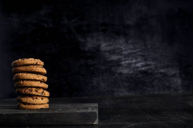 Siyah arka plandaki tahta masada bir yığın çikolatalı kurabiye.