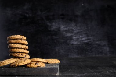 Siyah arka plandaki tahta masada bir yığın çikolatalı kurabiye.