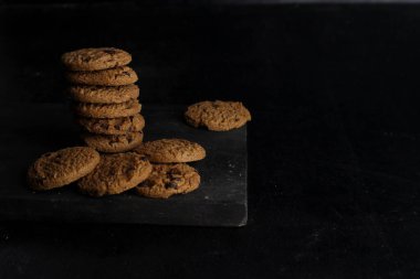 Siyah arka plandaki tahta masada bir yığın çikolatalı kurabiye.