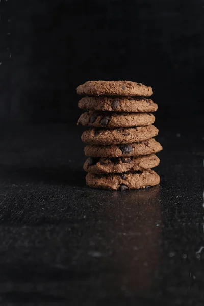黒を基調とした木製のテーブルの上にチョコレートクッキーの山 — ストック写真