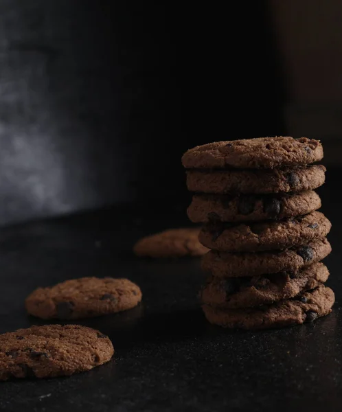 黒を基調とした木製のテーブルの上にチョコレートクッキーの山 — ストック写真