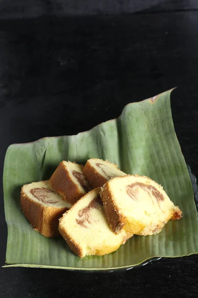 Siyah arka planda muz yaprağı kabında kek