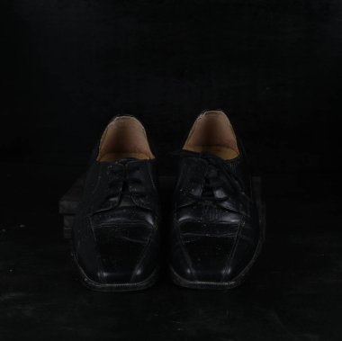 Pair of black male classic shoes on black background. Dusty shoes