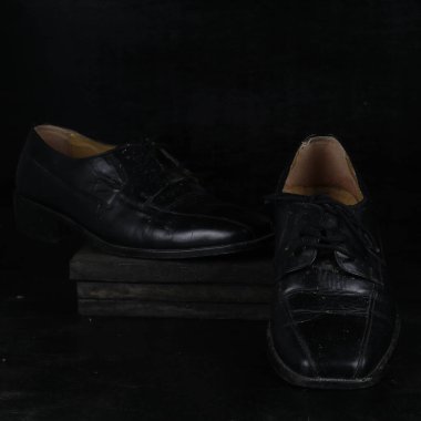Pair of black male classic shoes on black background. Dusty shoes