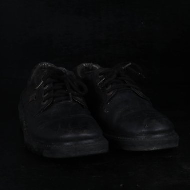 Pair of black male classic shoes on black background. Dusty shoes