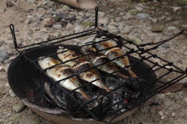 the process of making grilled fish that is burned over coconut shell coals