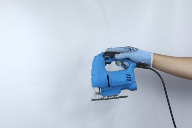 Eldiven tutan elektrikli testere makinesi beyaz arkaplanda izole edilmiş.