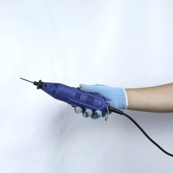 Eldiven tutan küçük elektrikli matkap beyaz arkaplanda izole edilmiş.