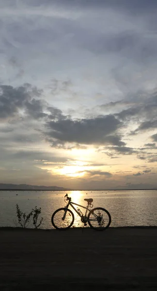 湖の夕日を背景に自転車のシルエットが — ストック写真