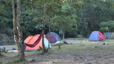 Güneşin doğuşunda nehirde kamp çadırıyla güzel bir sabah manzarası.