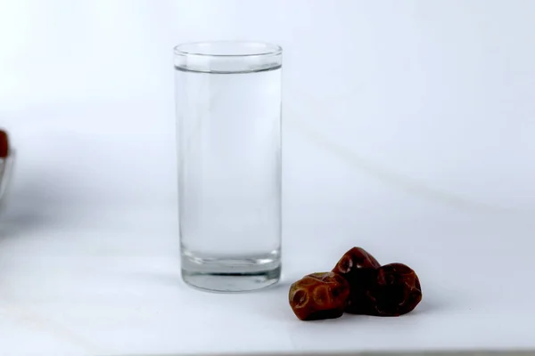 Ημερομηνίες Και Ένα Ποτήρι Νερό Απομονωμένο Λευκό Φόντο — Φωτογραφία Αρχείου