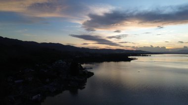 Göl ve dağların yanındaki yolun havadan görünüşü