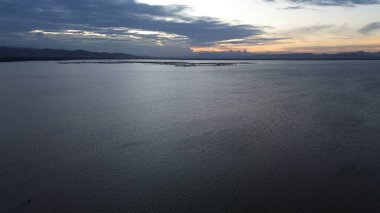 Gölün sularının üzerinde gün batımı manzarası ve güneş yansımaları olan hava manzarası. Göl manzaralı. Suyun üzerinde uçmak. Sakin göl yüzeyinde uçuş