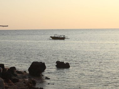 günbatımı denizde teknede silüeti