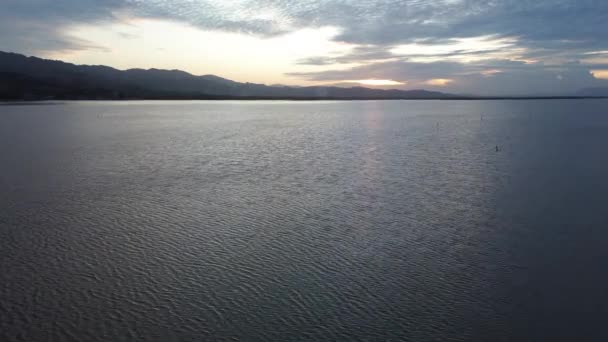 日没の景色と太陽の反射を望む湖の水上空からの眺め 湖の空からの眺め 水の上を飛んでいる 穏やかな湖の表面上のフライト — ストック動画