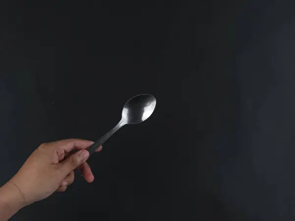 hand holding a spoon isolated on black background