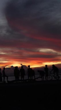 Vertical video of Silhouette of a group of people by the lake with a beautiful sunset