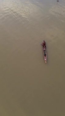 Vertical drone footage of a fisherman on his boat in the lake. Vertical video of fisherman fishing in the lake