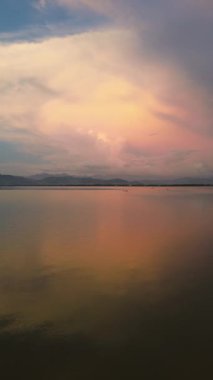 Vertical drone footage of Limboto Lake and mountains at sunset
