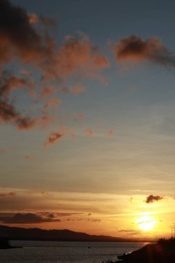 Arka planda Dağlar ve Bulutlarla Gölün Üzerinden Gün Batımı