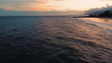 Gün batımında okyanus dalgalarının havadan görüntüsü. Okyanus dalgalarının üzerinde gün batımı Kumu temizler