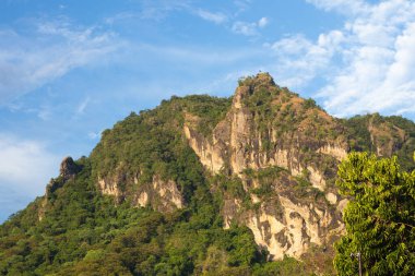 Yeşil ağaçlar ve berrak mavi gökyüzü ile Tepelerin ve sıradağların manzarası