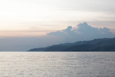 Deniz üzerinde gün batımı ve arka planda dağlar, Endonezya.